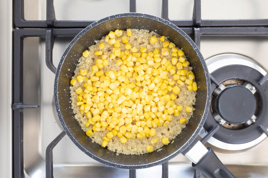 Corn and quinoa cooking in a pot on the stovetop.