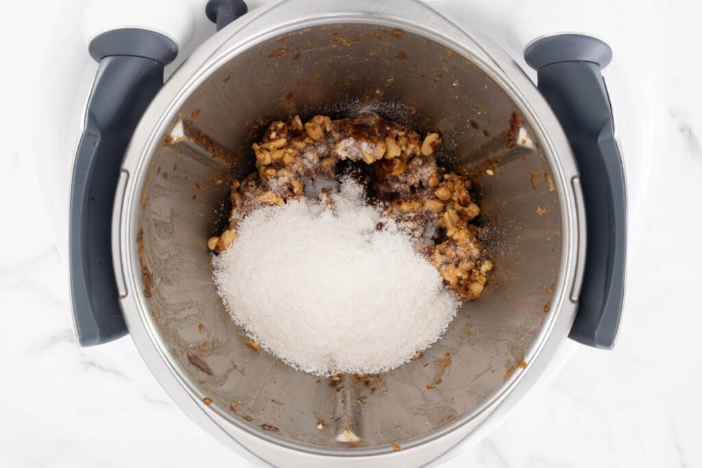 Step 3 of Peanut Caramel Bliss Balls process in a Thermomix, adding the coconut, vanilla paste and salt.