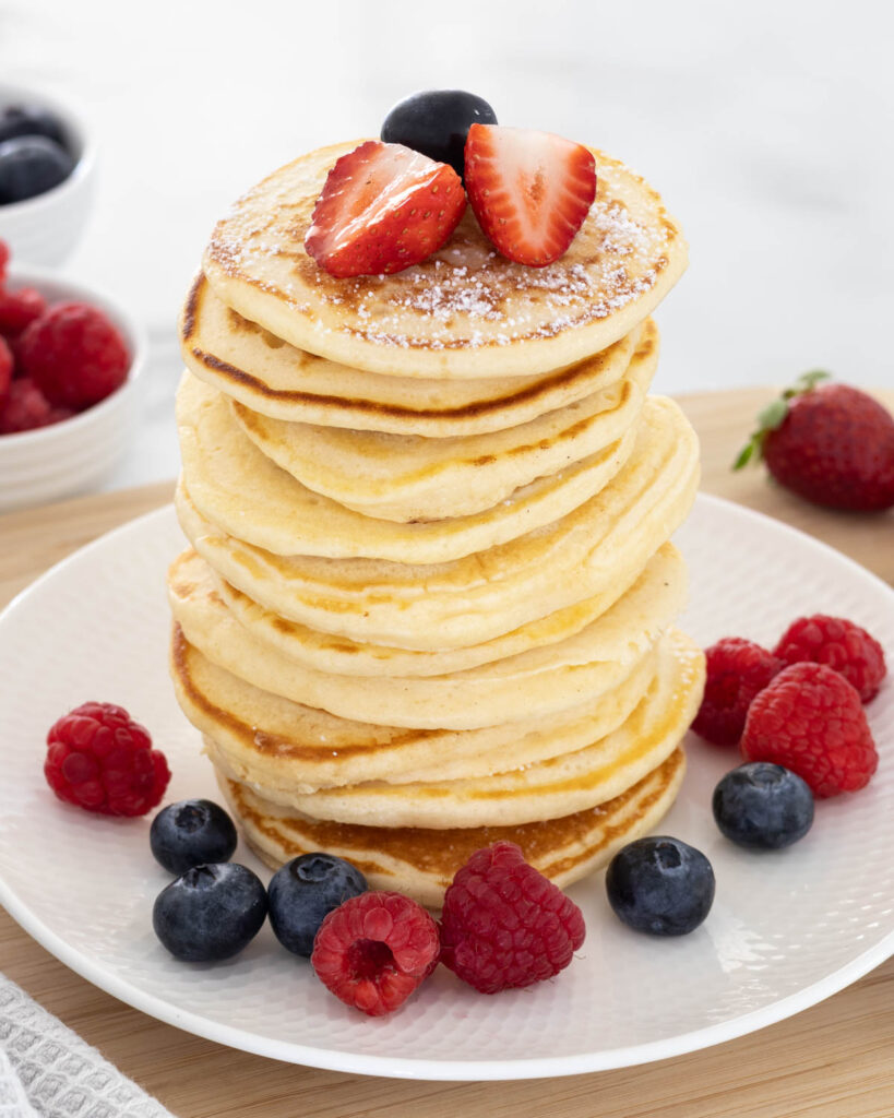 Small Batch Mini Pancakes stacked on a plate and garnished with fresh berries.